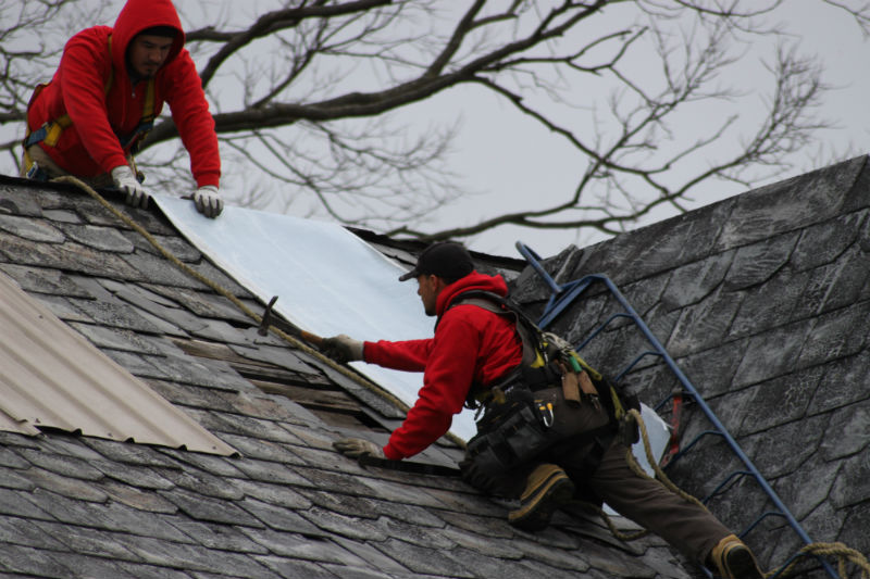 Durable Slate roofers attach temporary patches to the historic farmhouse